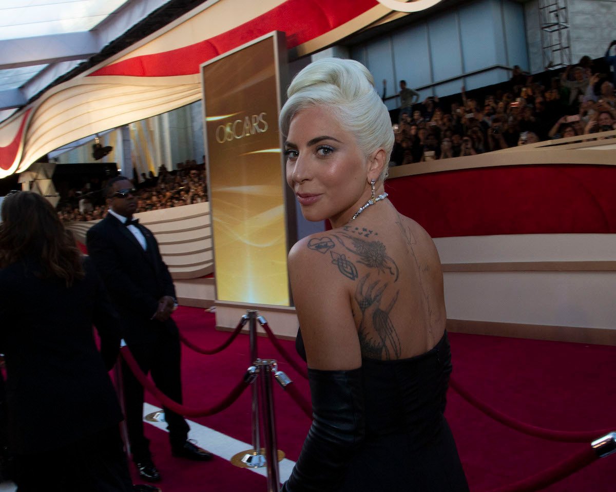 Lady Gaga turns and smiles in a black dress at the Oscars