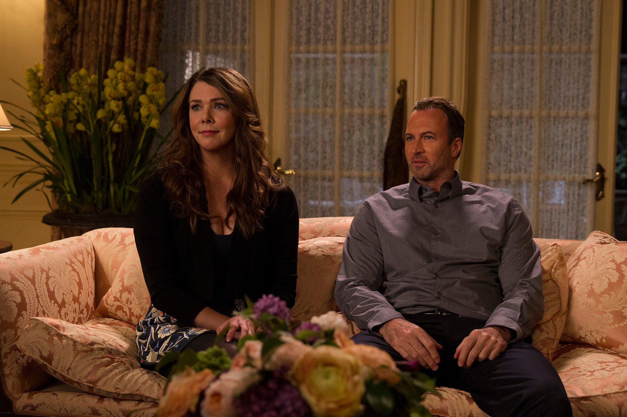 Lauren Graham and Scott Patterson sit on a couch in 'Gilmore Girls: A Year in the Life'