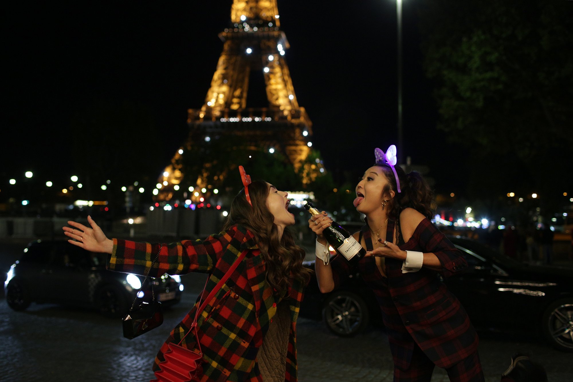 Lily Collins and Ashley Park on the set of 'Emily in Paris' drinking champagne in front of the Eiffel Tower