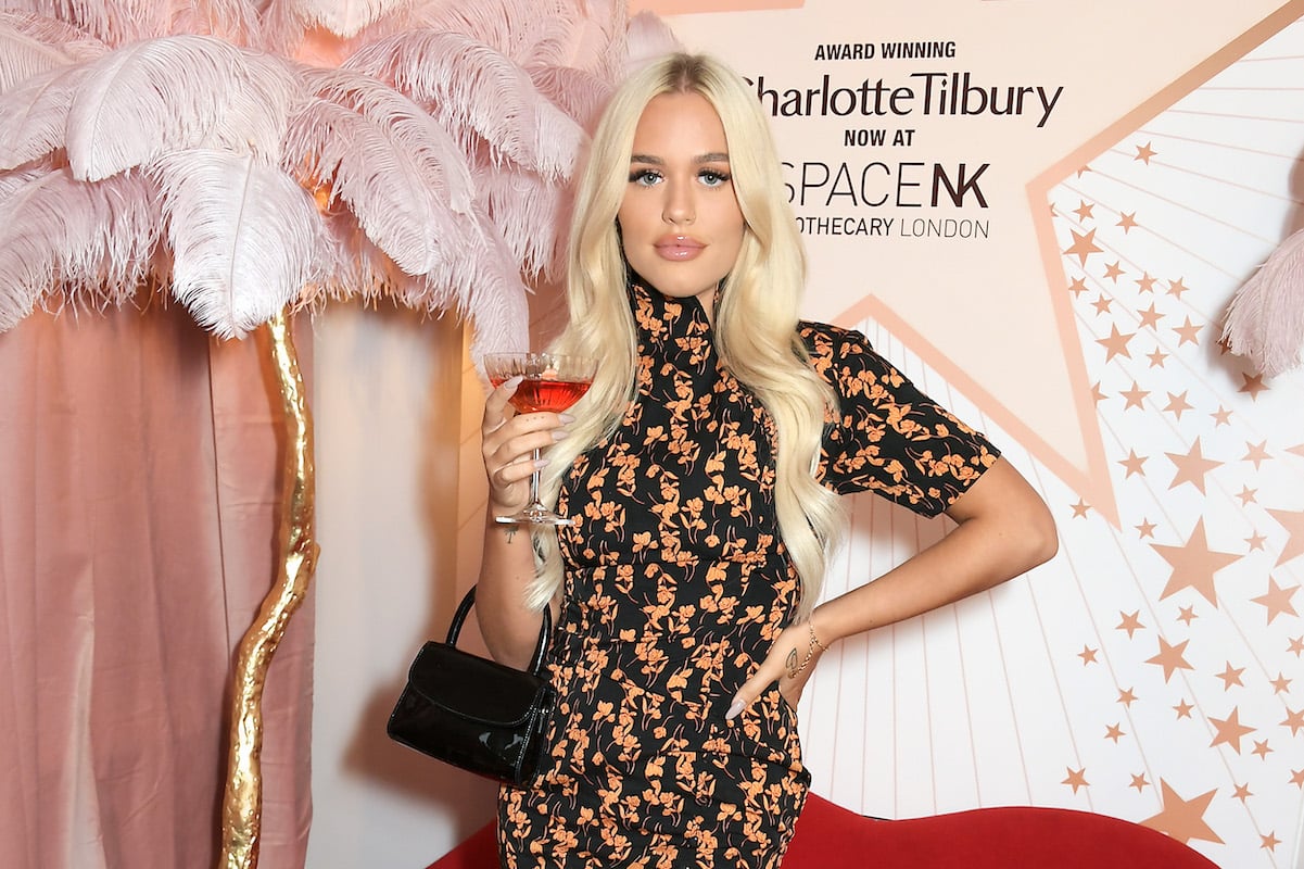 One Direction member Louis Tomlinson's sister Lottie in a floral dress holding a drink