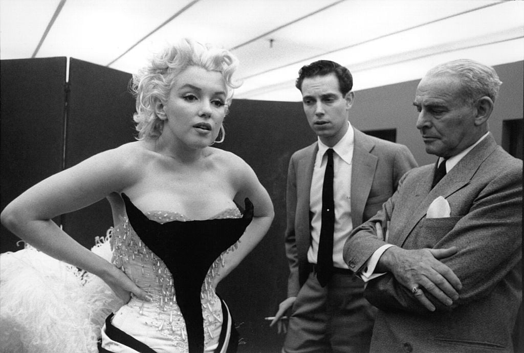 Marilyn Monroe is being fitted for a costume while two men look on.