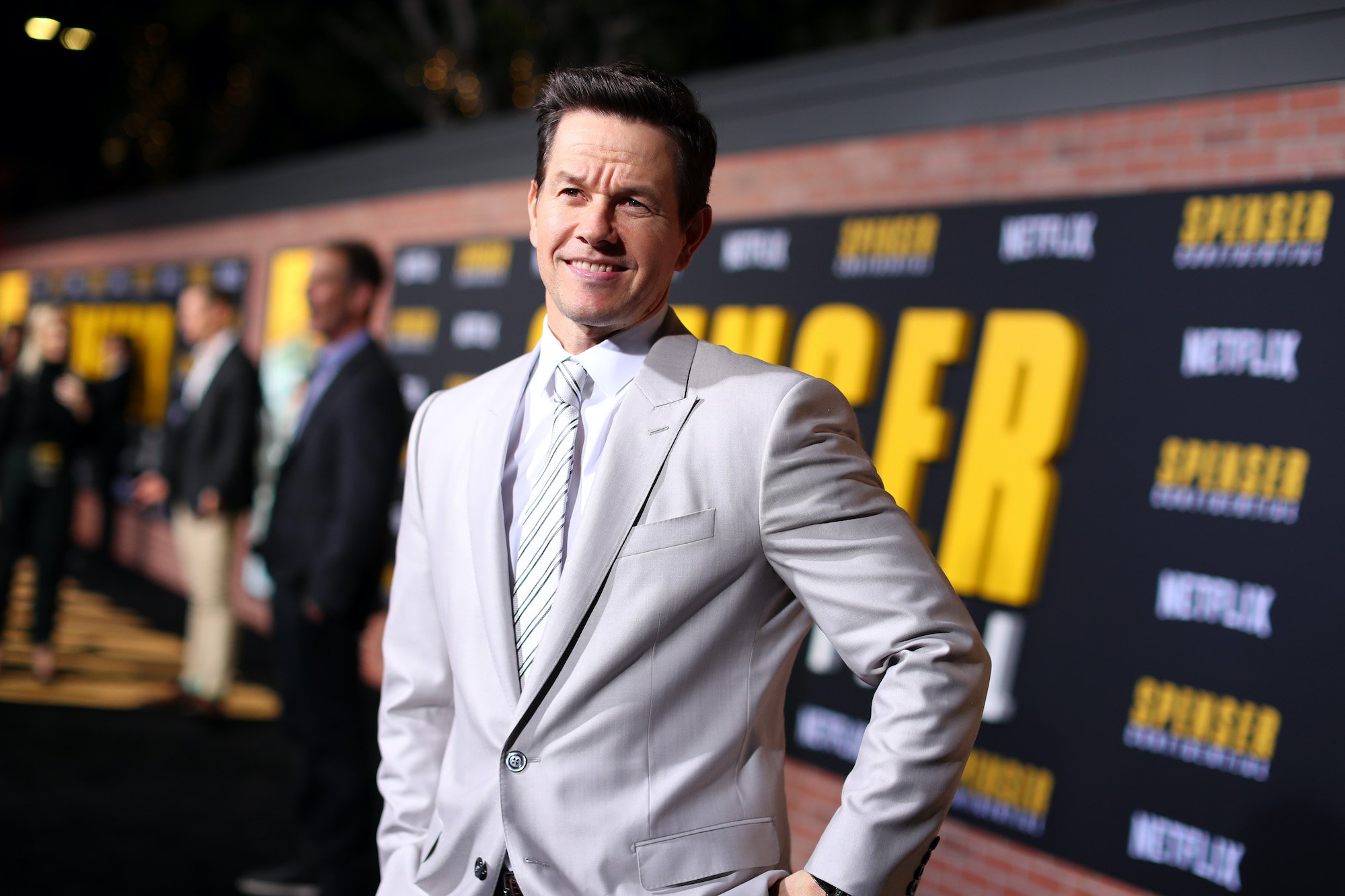 Mark Wahlberg smiling in front of a dark background