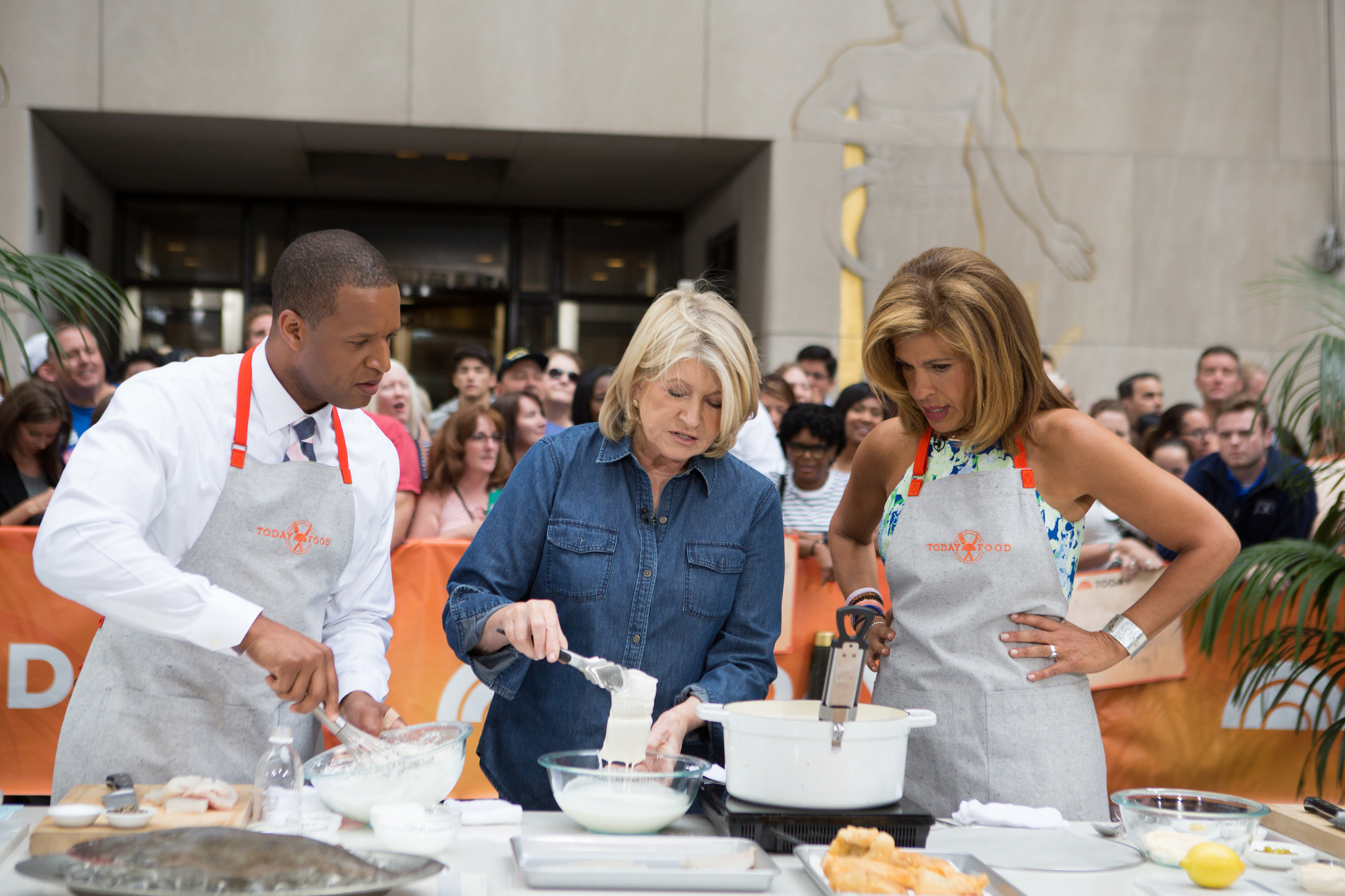 Craig Melvin, Martha Stewart, and Hoda Kotb around a burner cooking Martha Stewart's recipe