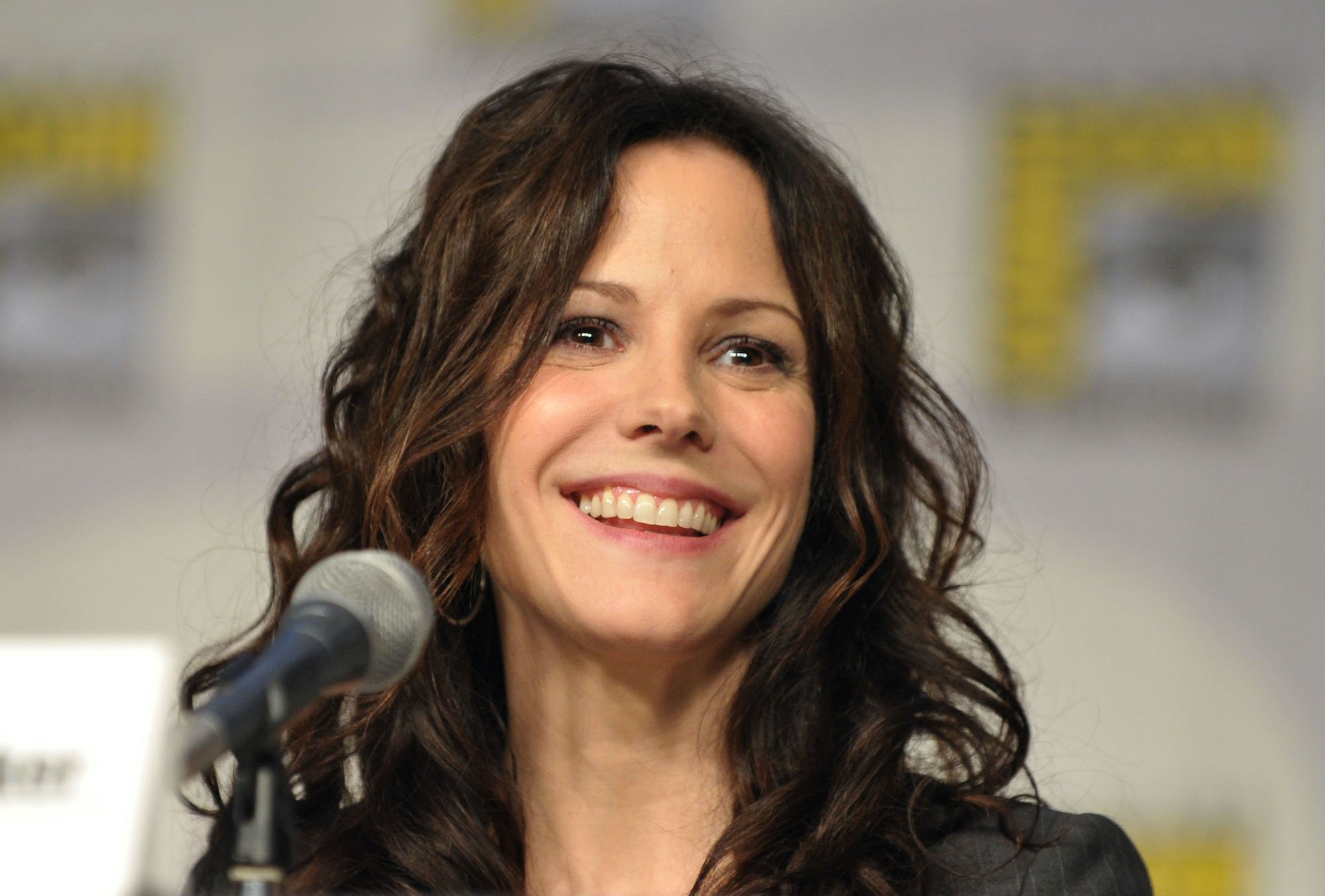 Mary-Louise Parker smiling, seated behind a microphone