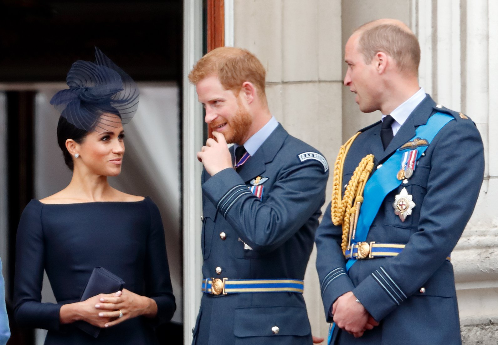 Meghan Markle, Prince Harry, and Prince William, standing on the balcony of Buckingham Palace for a flypast in 2018