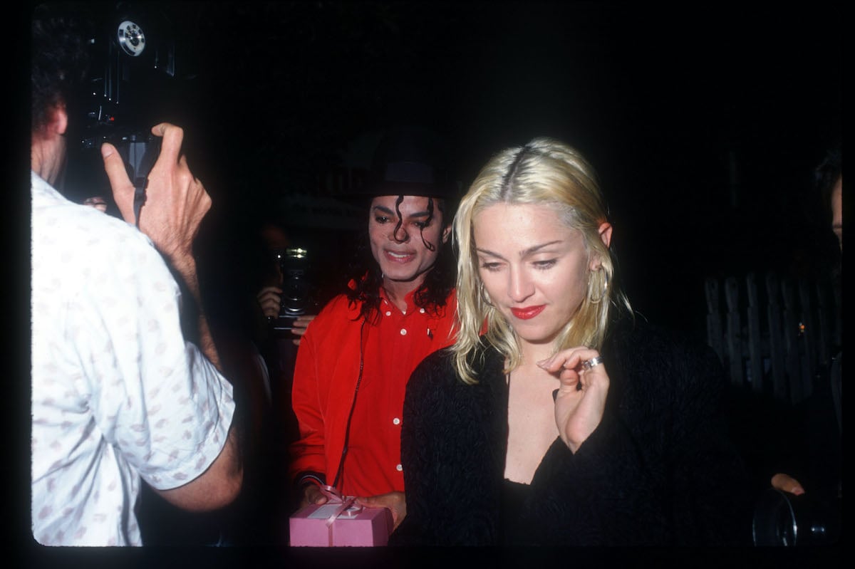 Michael Jackson -- wearing red clothes and a black hat -- and Madonna, wearing black, pass a photographer in 1991