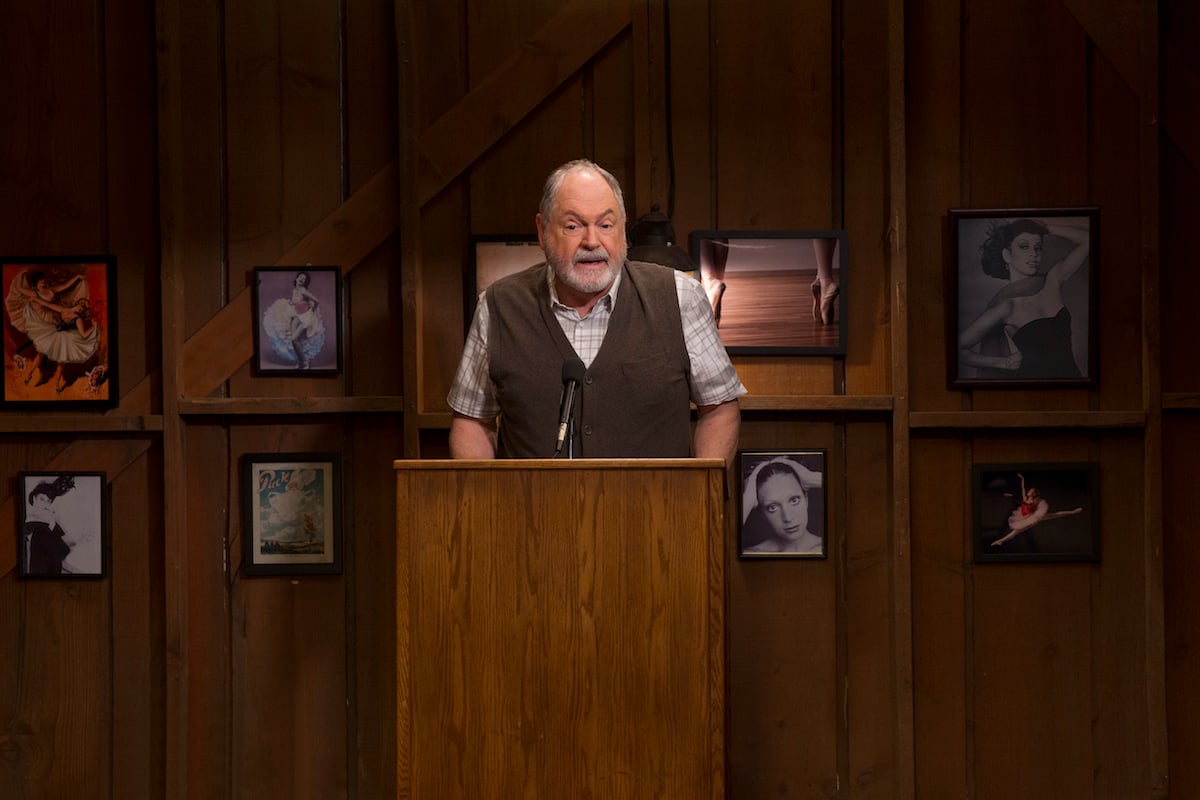 Michael Winters stands behind a podium on the set of 'Gilmore Girls: A Year in the Life'
