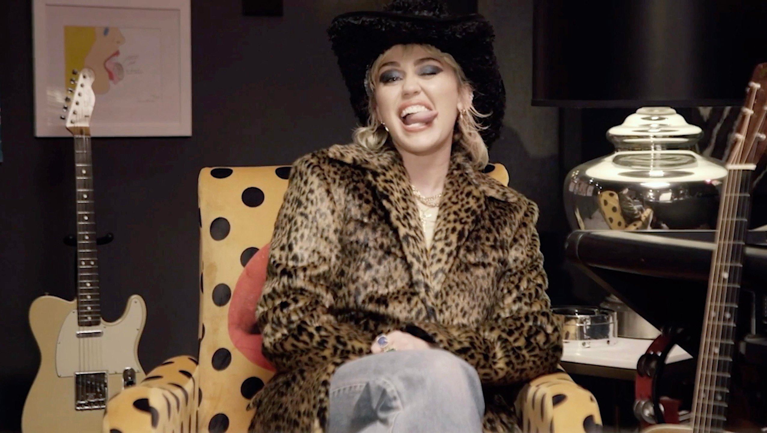 Miley Cyrus age 28 sticks her tongue out while wearing a fur coat and cowboy hat