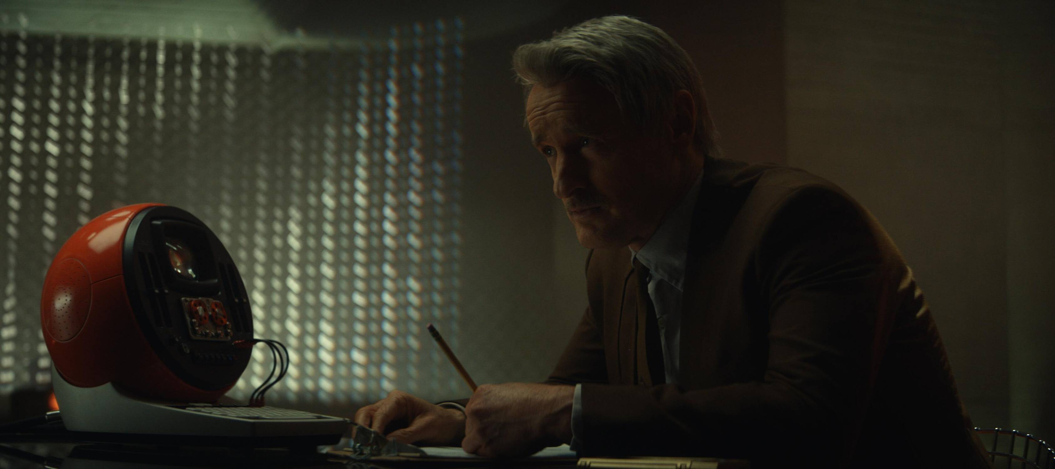 Mobis actor Owen Wilson sits at his desk holding a pencil