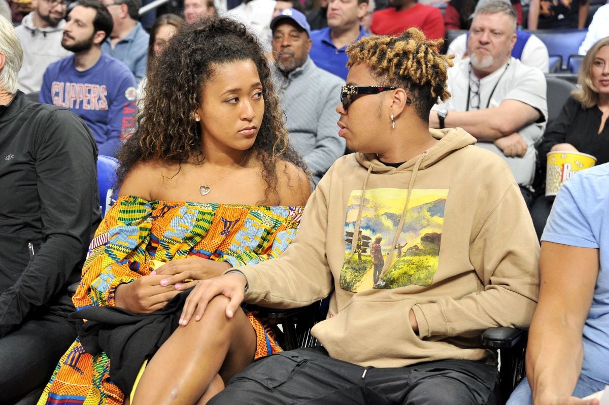 Naomi Osaka and Cordae sit courtside at a basketball game