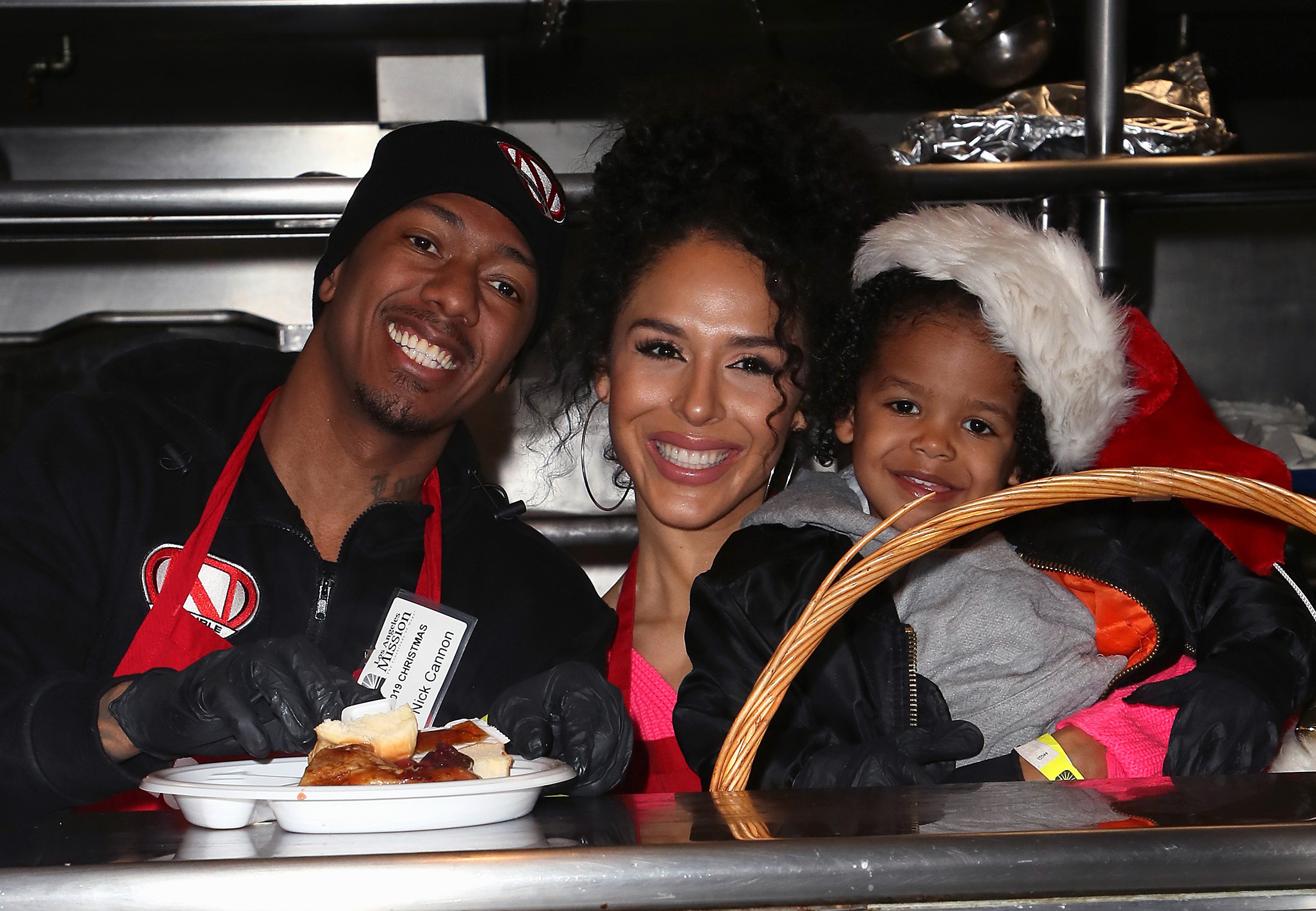 Nick Cannon, Brittany Bell, and their son Golden Cannon smiling for family photo at Christmas event for Los Angeles Mission