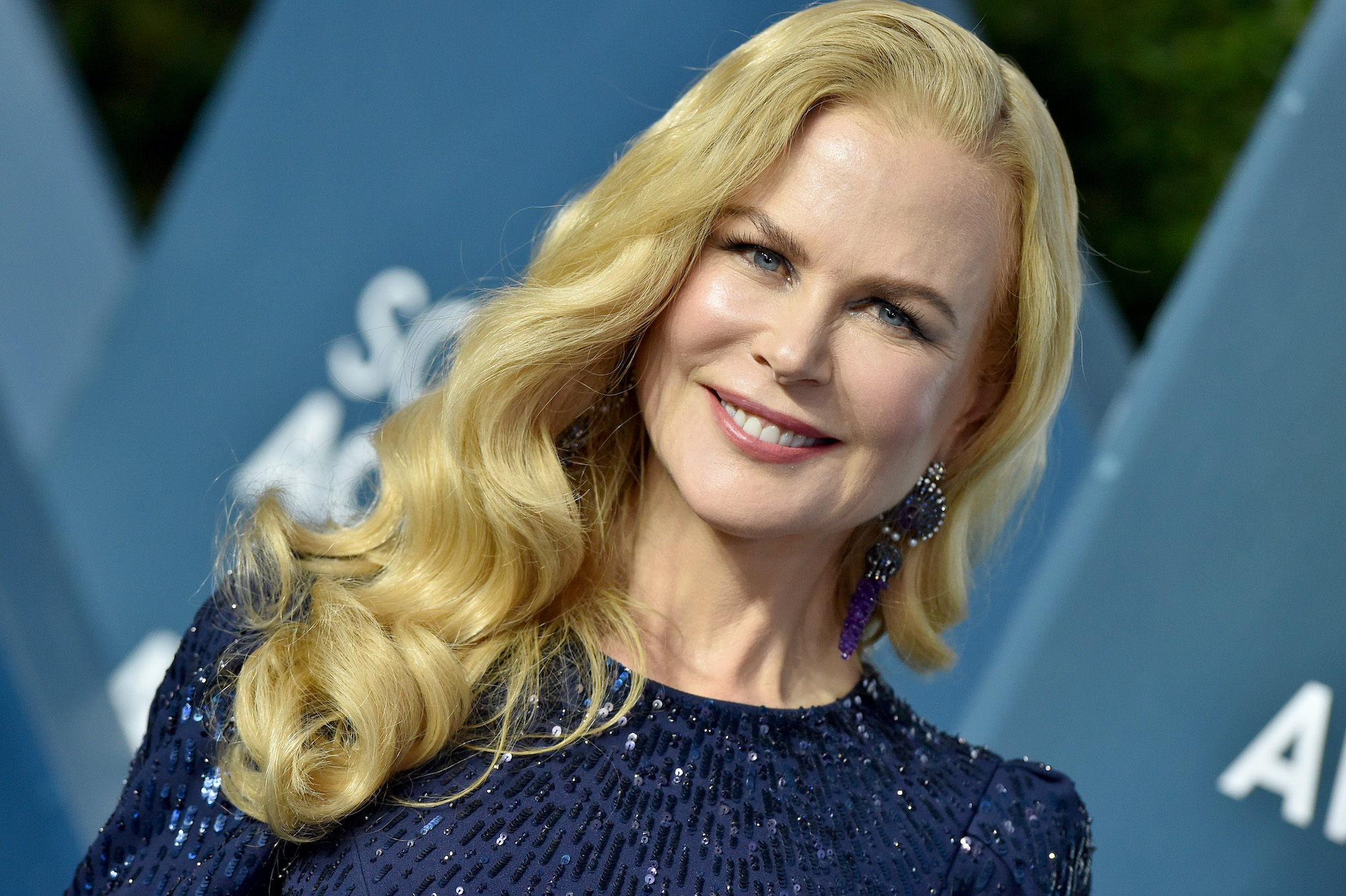 Nicole Kidman smiling in front of a blue background