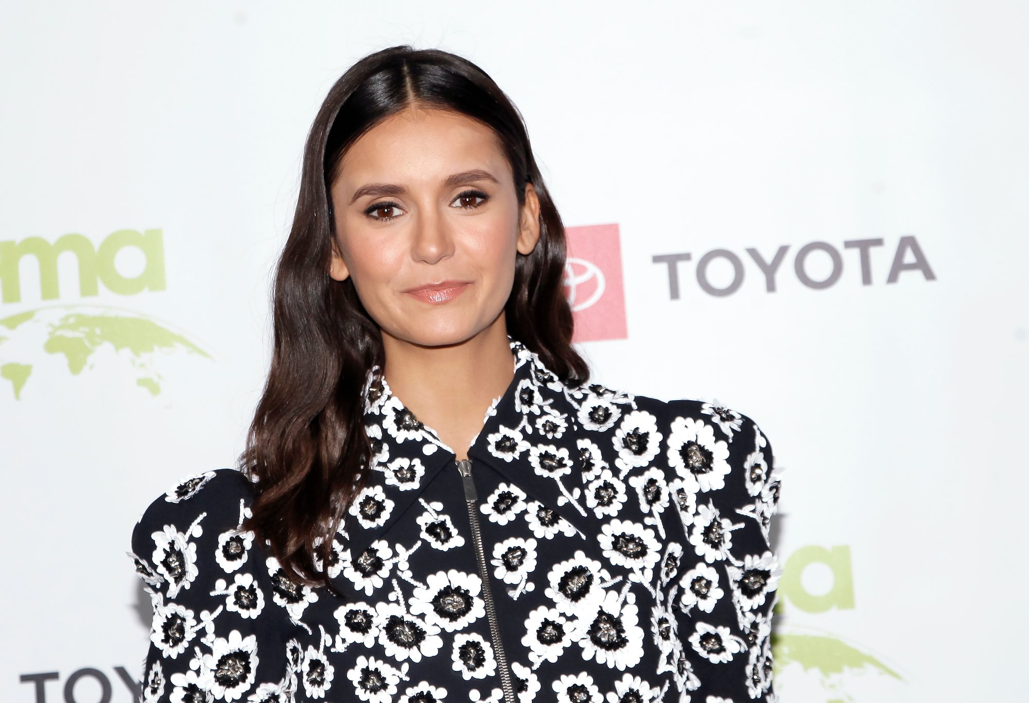 Nina Dobrev smiling in front of a white background