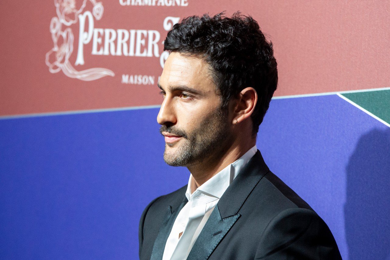 Noah Mills wears a suit and poses for cameras during an event in 2019.