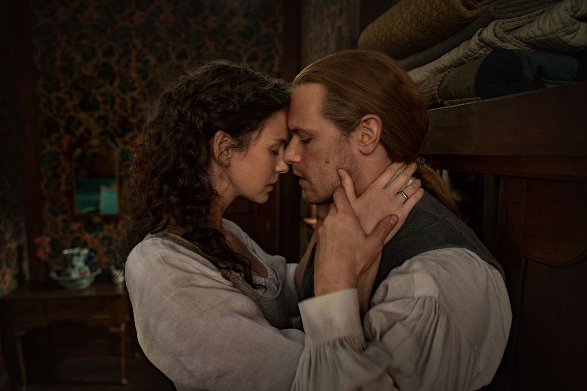 Caitriona Balfe and Sam Heughan embrace while wearing 1770s colonial clothing in 'Outlander' Season 6