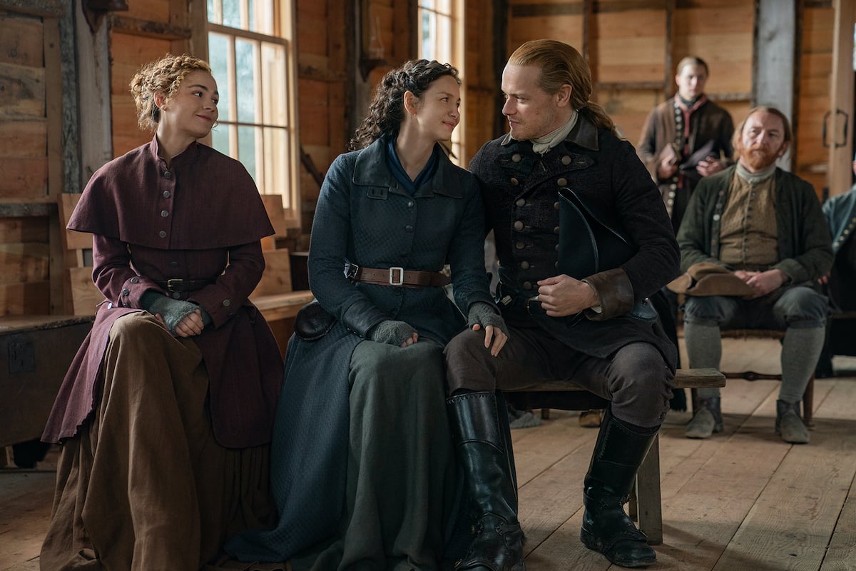 Outlander season 6 photo featuring Sophie Skelton, Caitriona Balfe, and Sam Heughan in 1770s colonial clothing as Brianna, Claire, and Jamie 