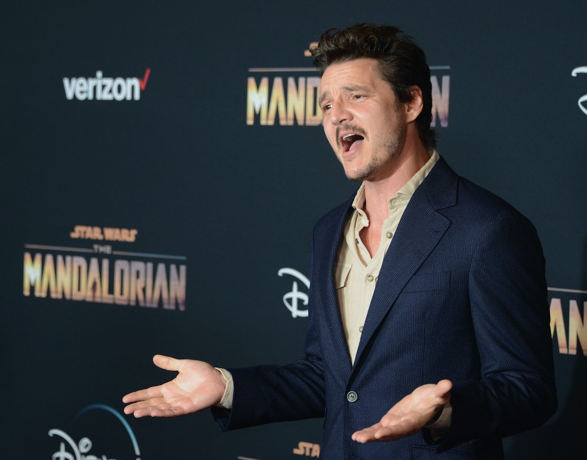 Pedro Pascal poses on the red carpet with his arms open at 'The Mandalorian' premiere