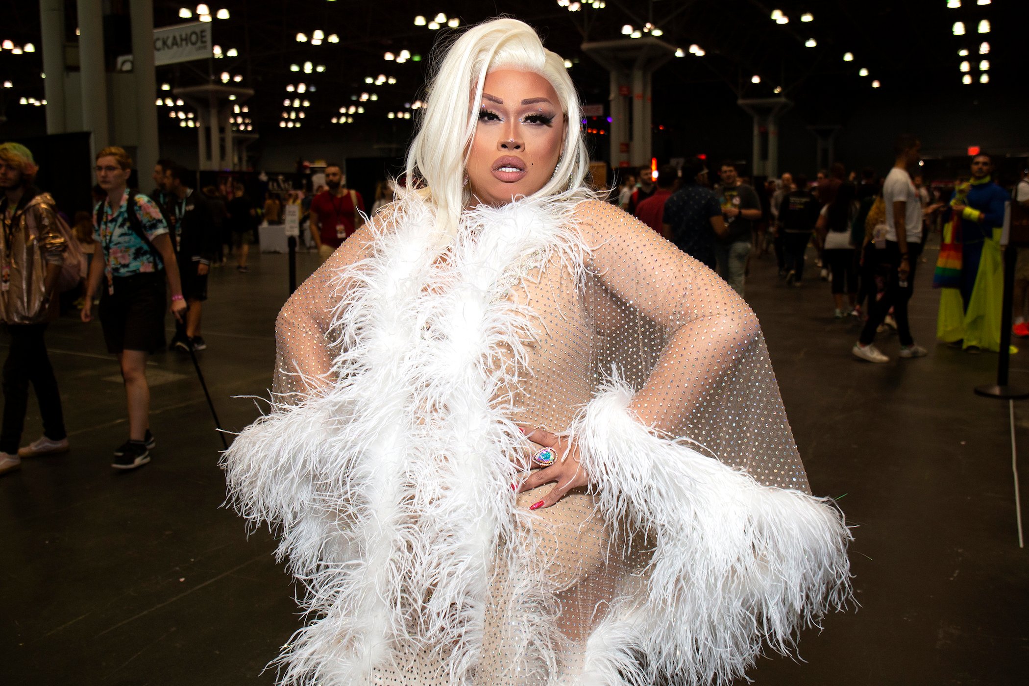 Jiggly Caliente attends RuPaul's DragCon 2019, dressed in white with blonde hair