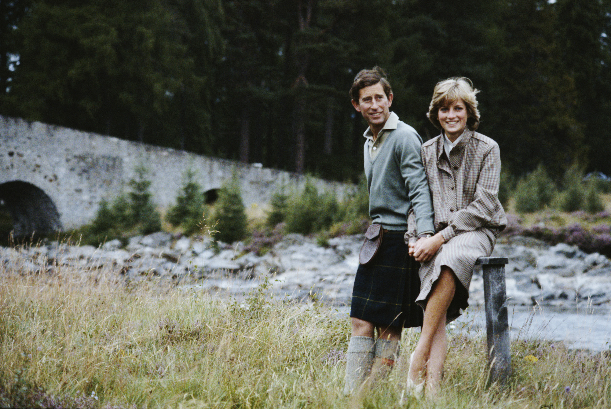 Prince Charles and Princess Diana smiling in front of a stream