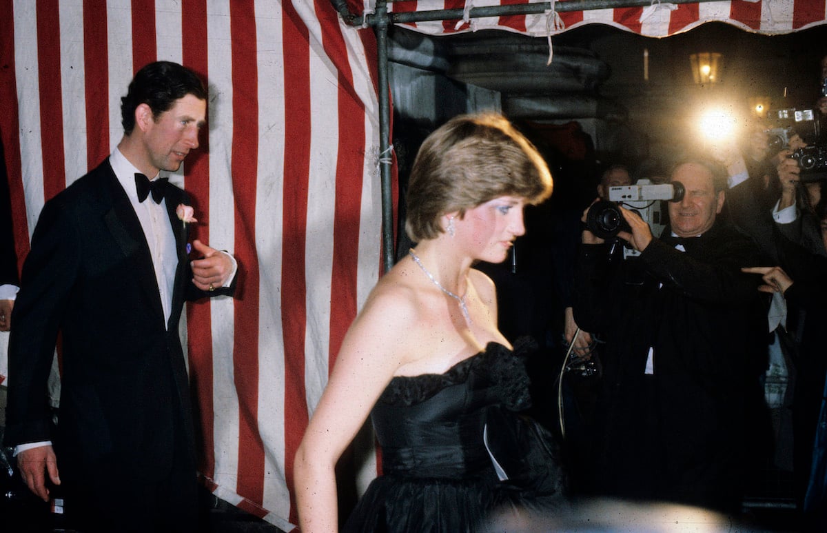 Prince Charles wears a tuxedo as he walks behind Princess Diana wearing a strapless gown 