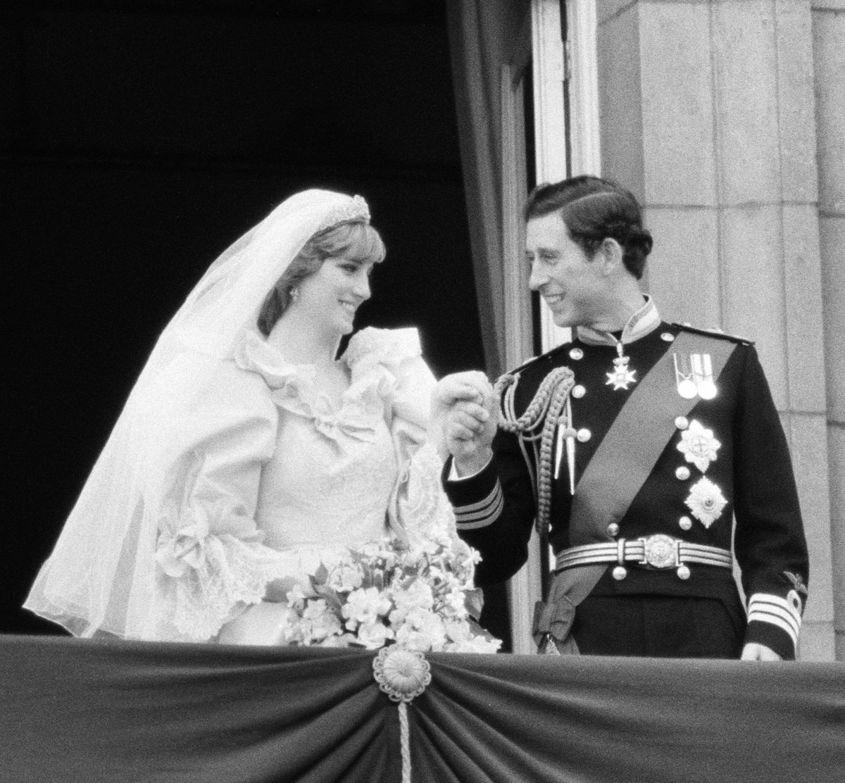 Princess Diana and Prince Charles holding hands and smiling on their wedding day