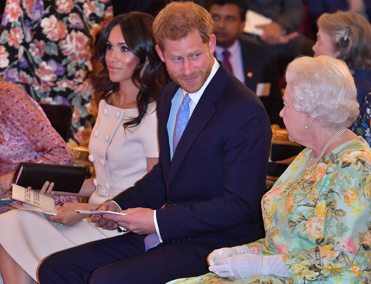 Meghan Markle, Prince Harry, and Queen Elizabeth seated in a row