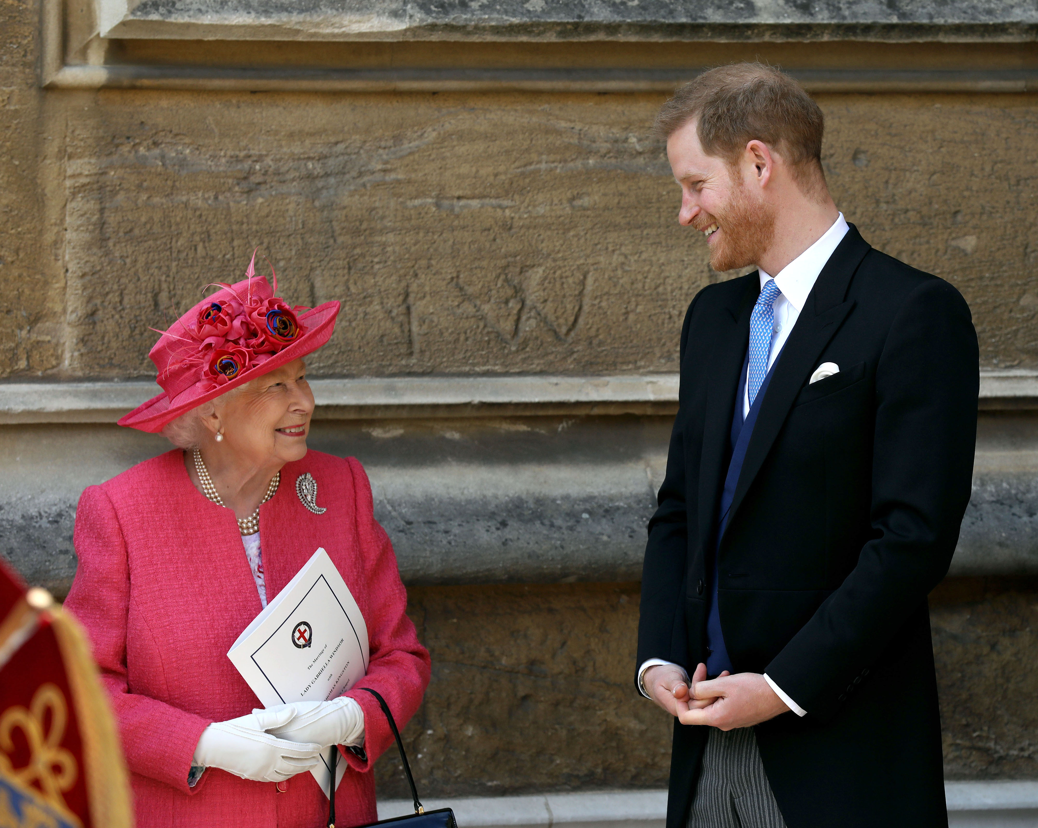 Queen Elizabeth II and Prince Harry talking and laughing as they leave the wedding of Lady Gabriella Windsor