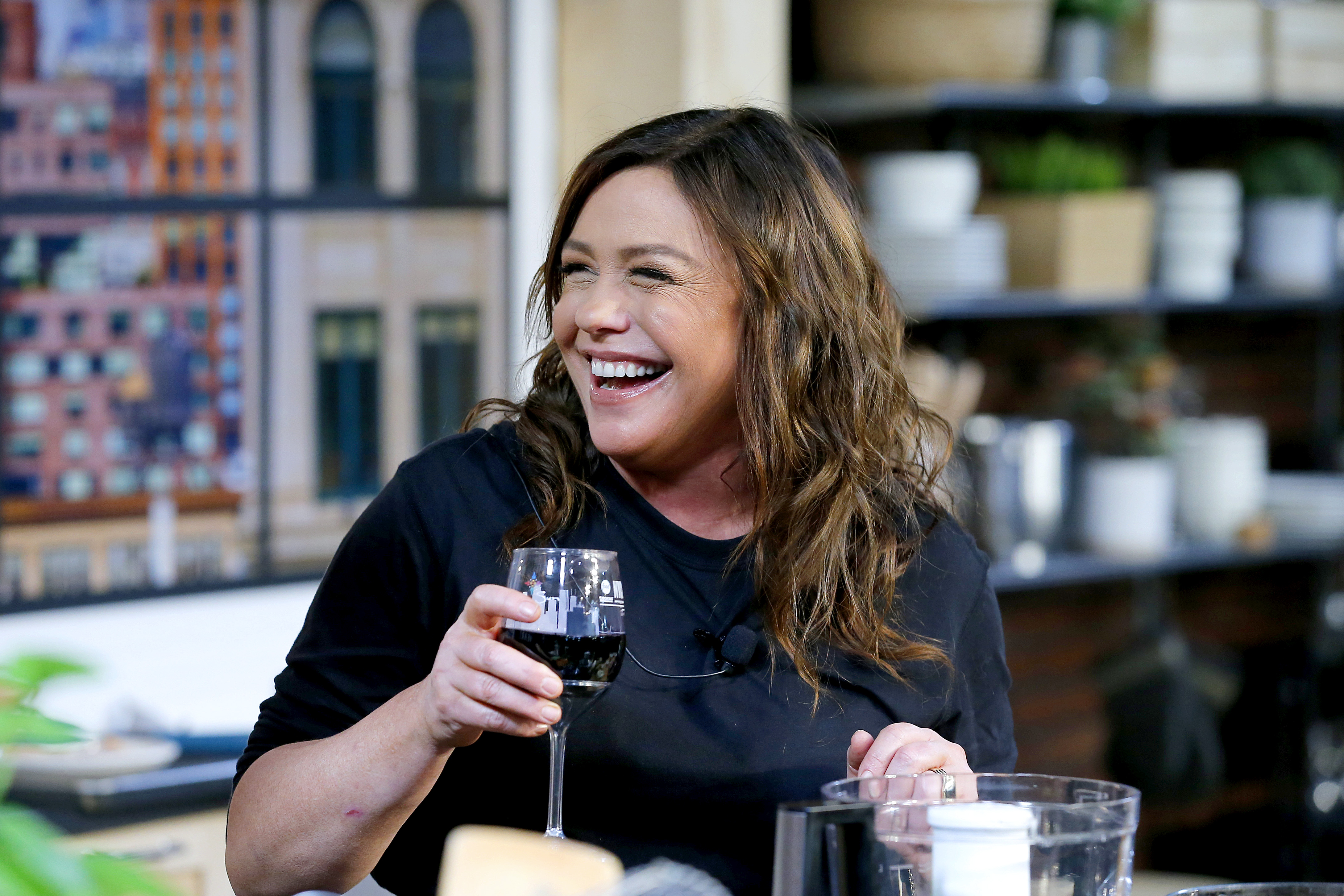 Rachael Ray smiling and holding a glass of wine