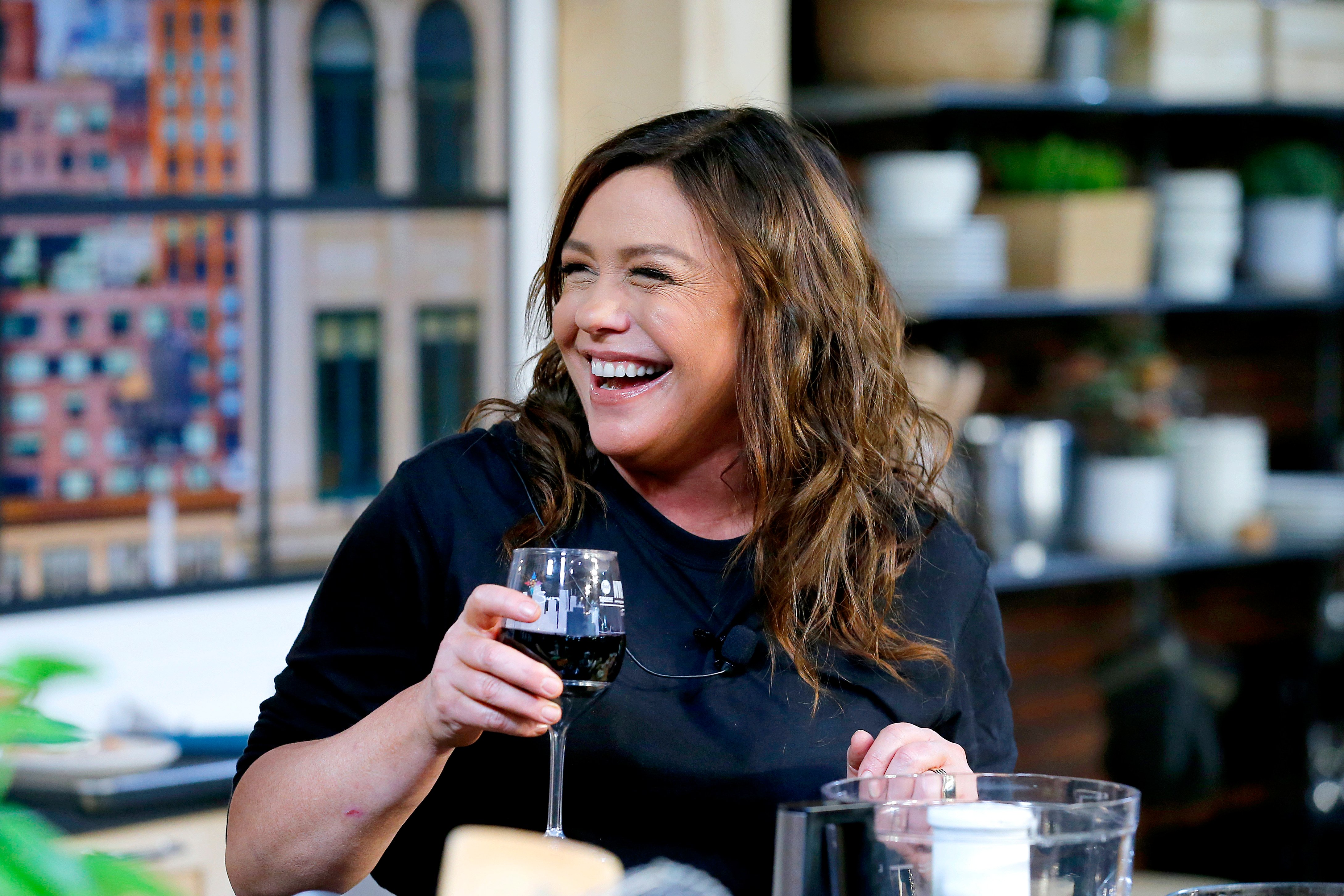 Rachael Ray smiling and holding a glass of wine