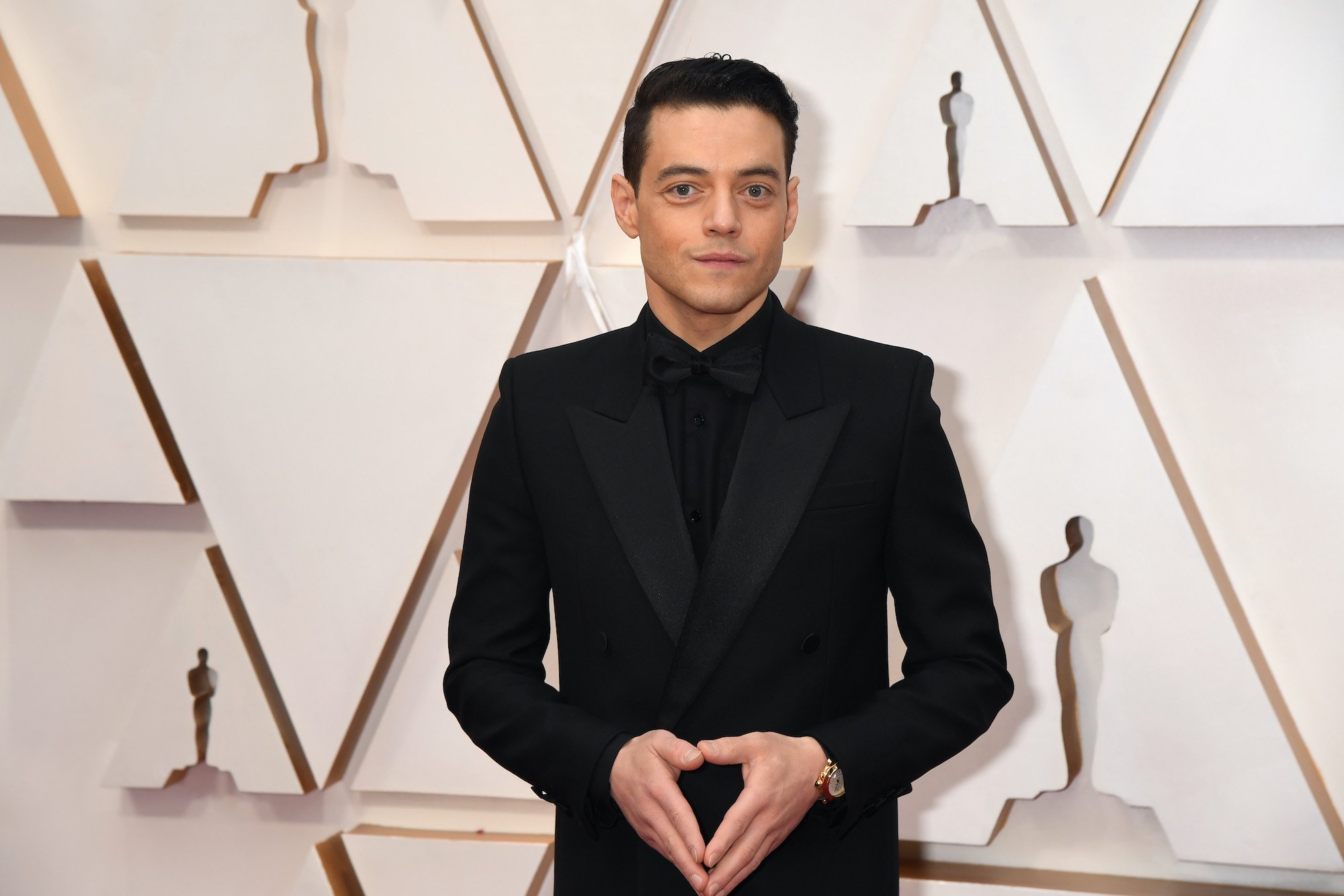 Rami Malek smiling in front of a white background