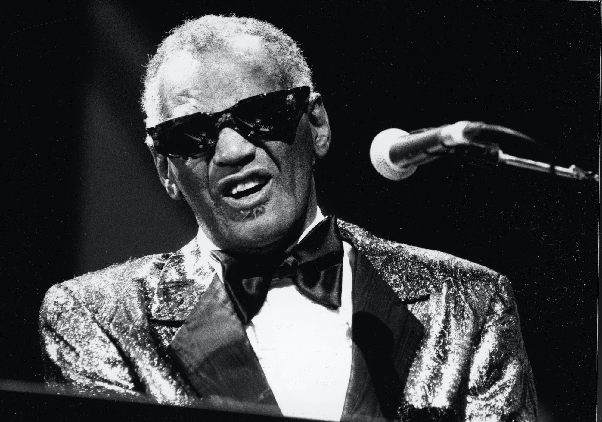 Ray Charles playing piano, singing into a microphone