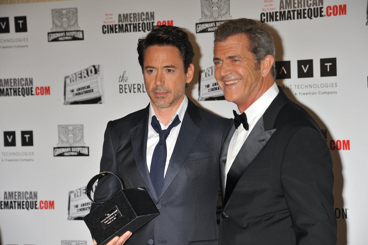 Robert Downey Jr. and Mel Gibson wear suits and pose at at the 25th Annual American Cinematheque Award