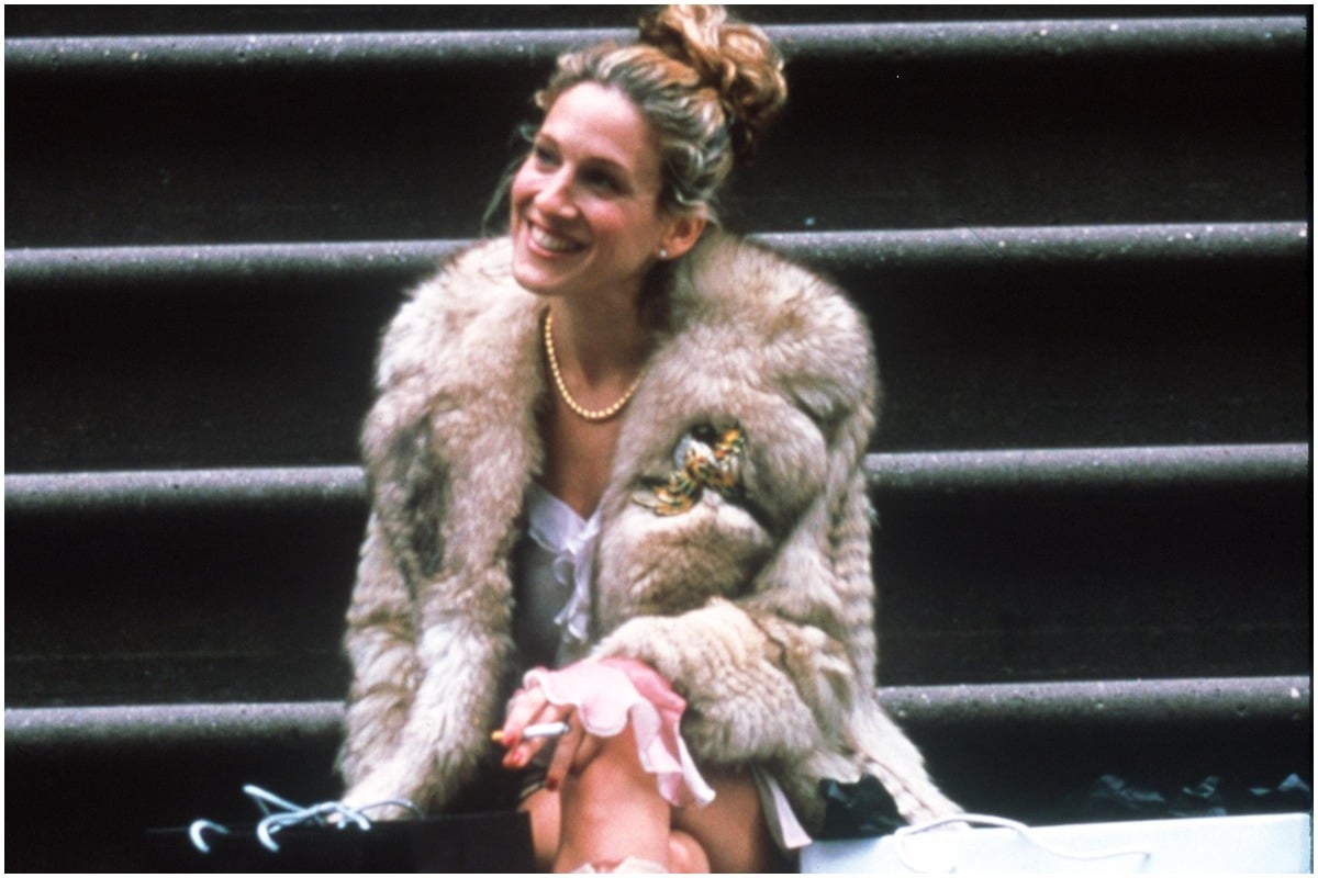 Sarah Jessica Parker smiling on a flight of stairs as Carrie Bradshaw in 'Sex and the City'