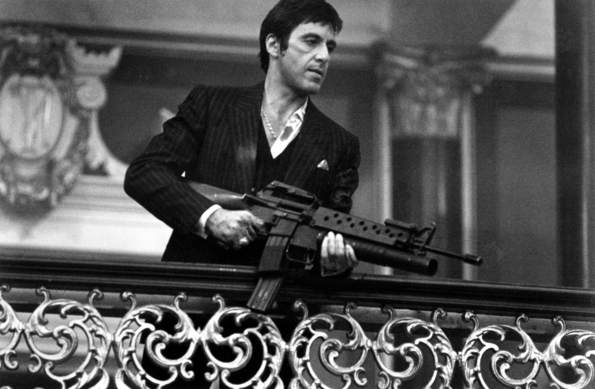 Al Pacino holding a machine gun over a balcony in 'Scarface'