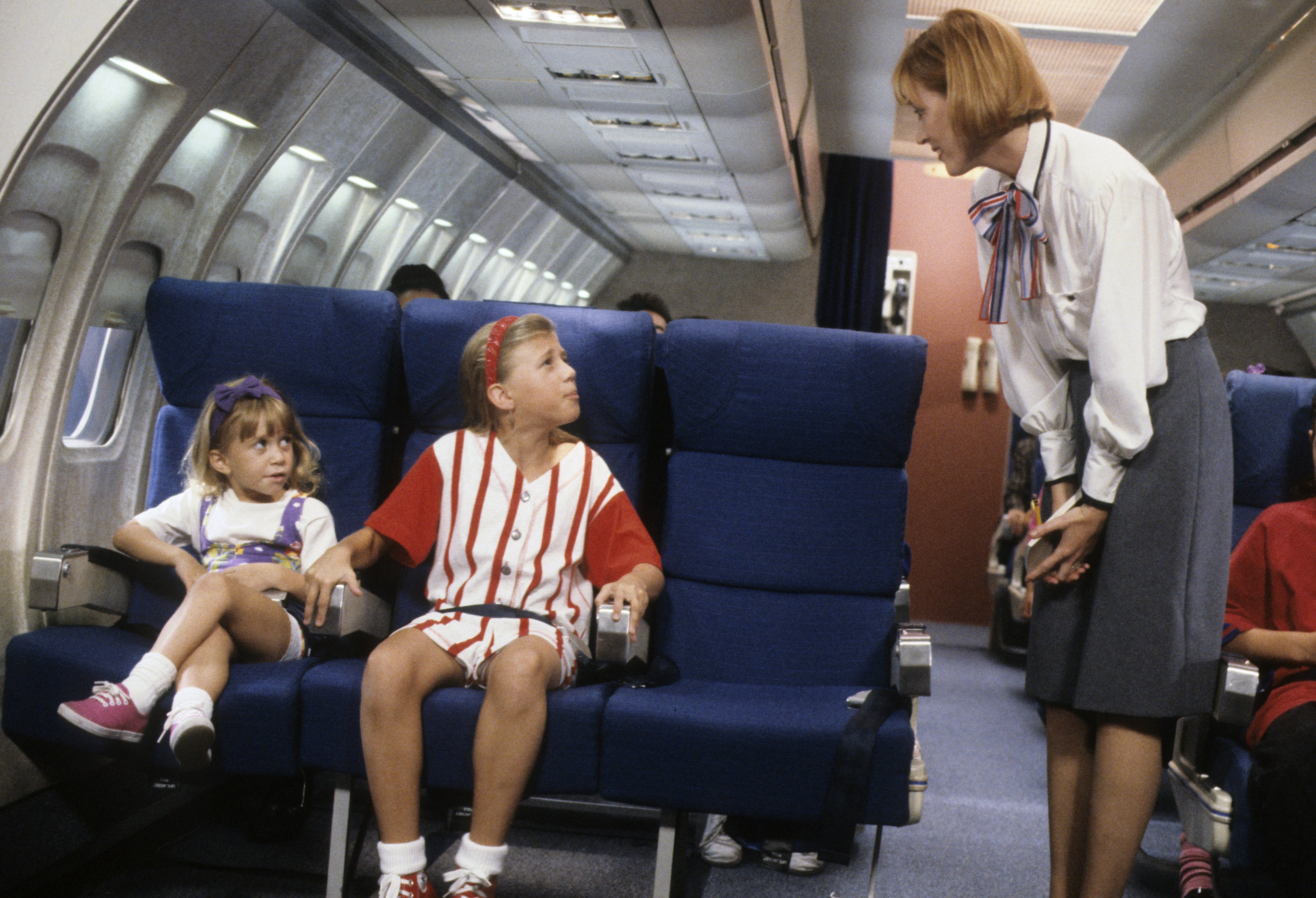 Michelle and Stephanie Tanner on an airplane talking to a flight attendant on an episode of 'Full House'