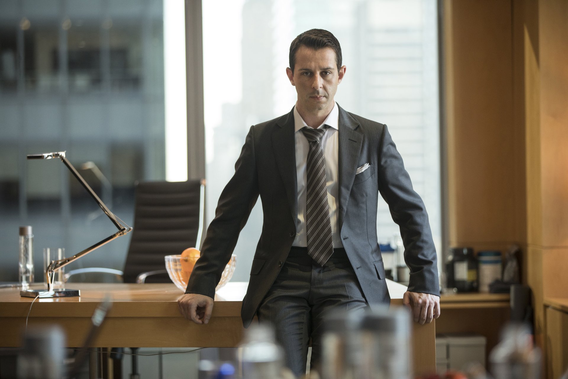 Jeremy Strong as Kendall Roy, standing in front of a desk