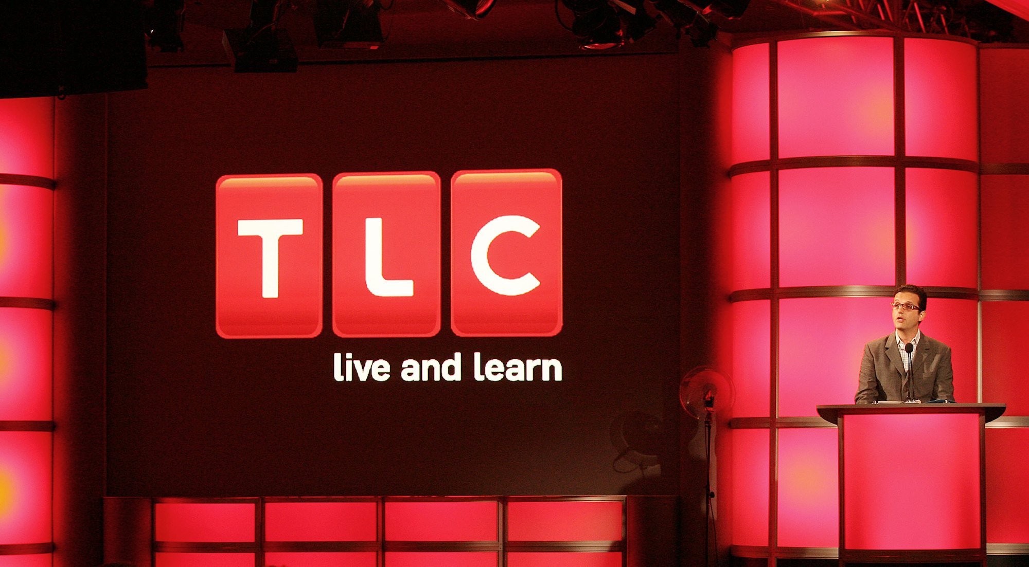 David Abraham speaks at a podium in front of the TLC logo
