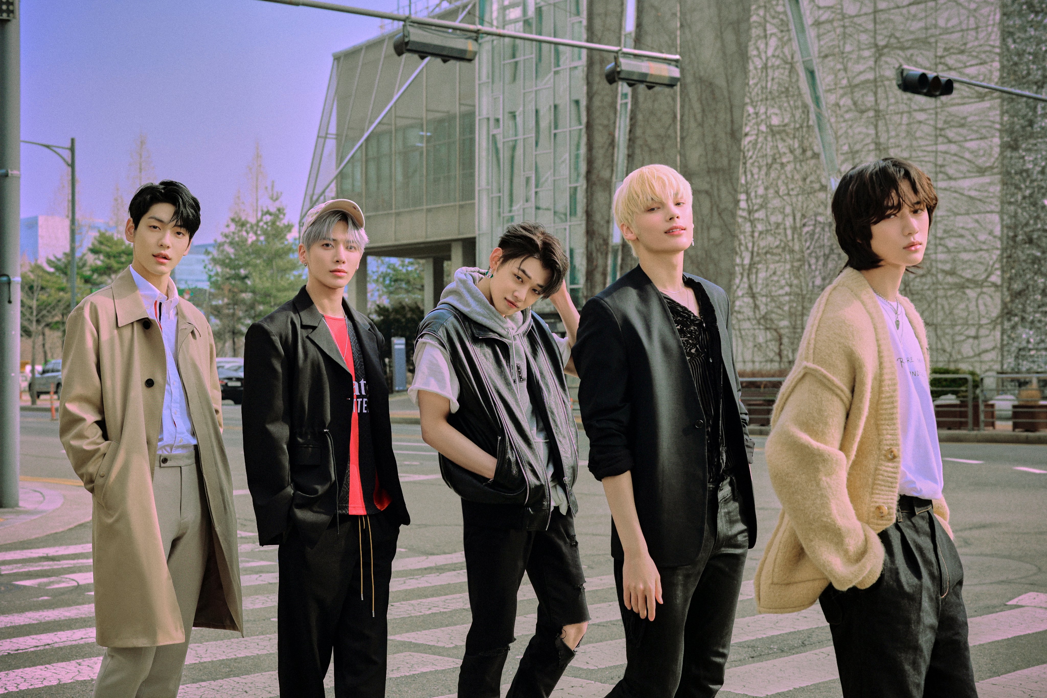 Soobin, Taehyun, Yeonjun, Huening Kai, and Beomgyu of TXT pose on the crosswalk of a street