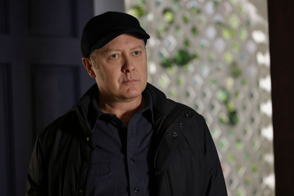 James Spader as Raymond Red' Reddington looks on. He's wearing a dark ball hat and matching jacket.