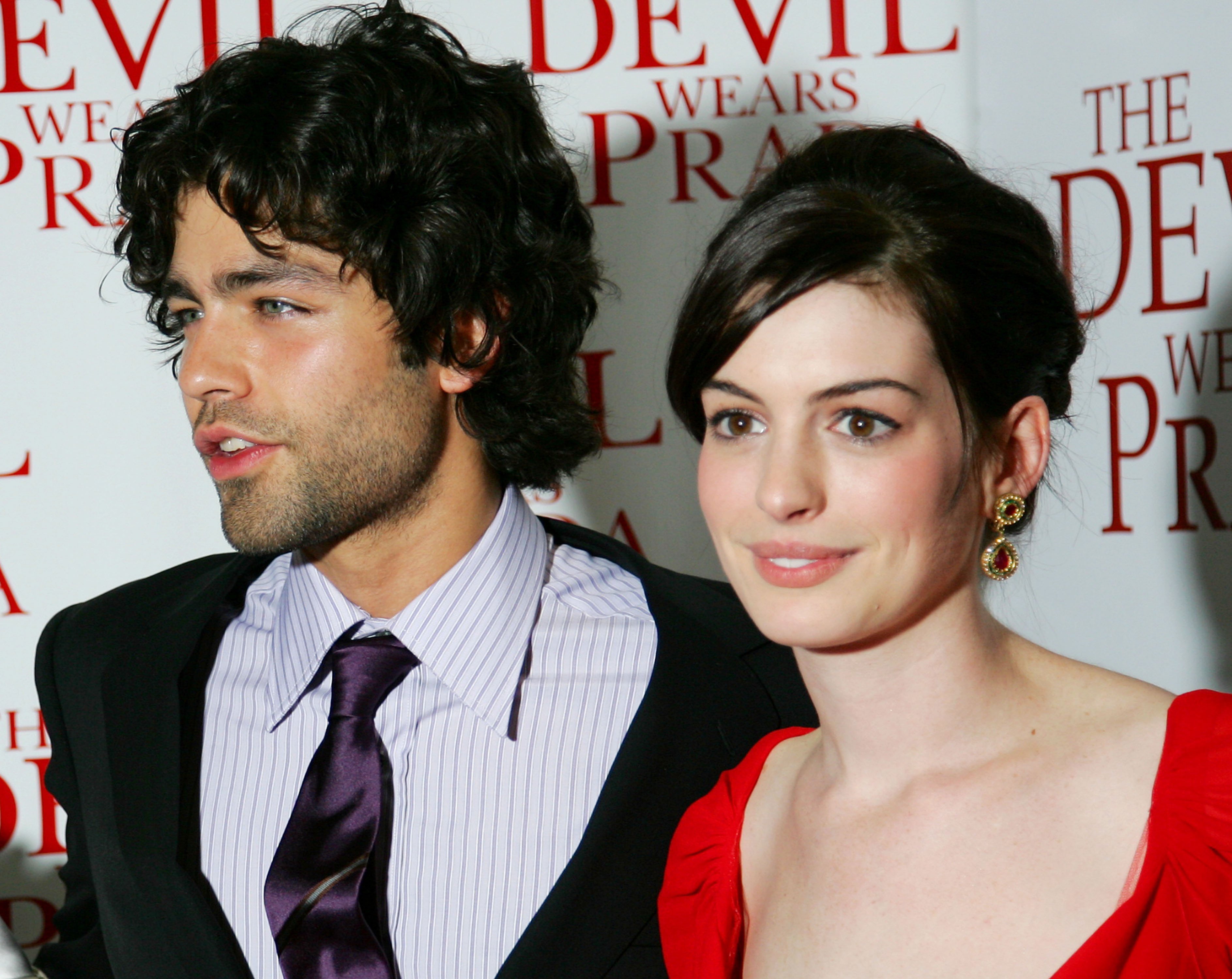'The Devil Wears Prada' actors Adrian Grenier and Anne Hathaway smiling and posing at movie's premiere.
