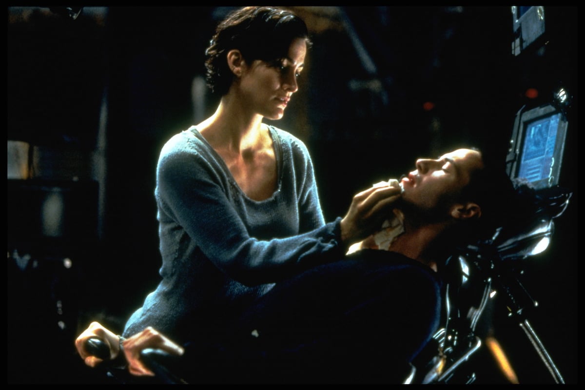 Trinity (Carrie-Anne Moss) stands over Neo (Keanu Reeves) in a scene from 'The Matrix'