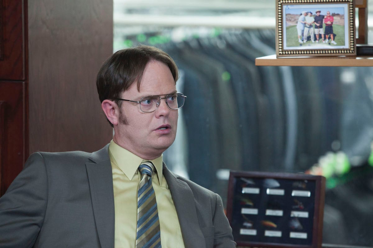 Rainn Wilson as Dwight Schrute sits in a clothing store full of suits on 'The Office'