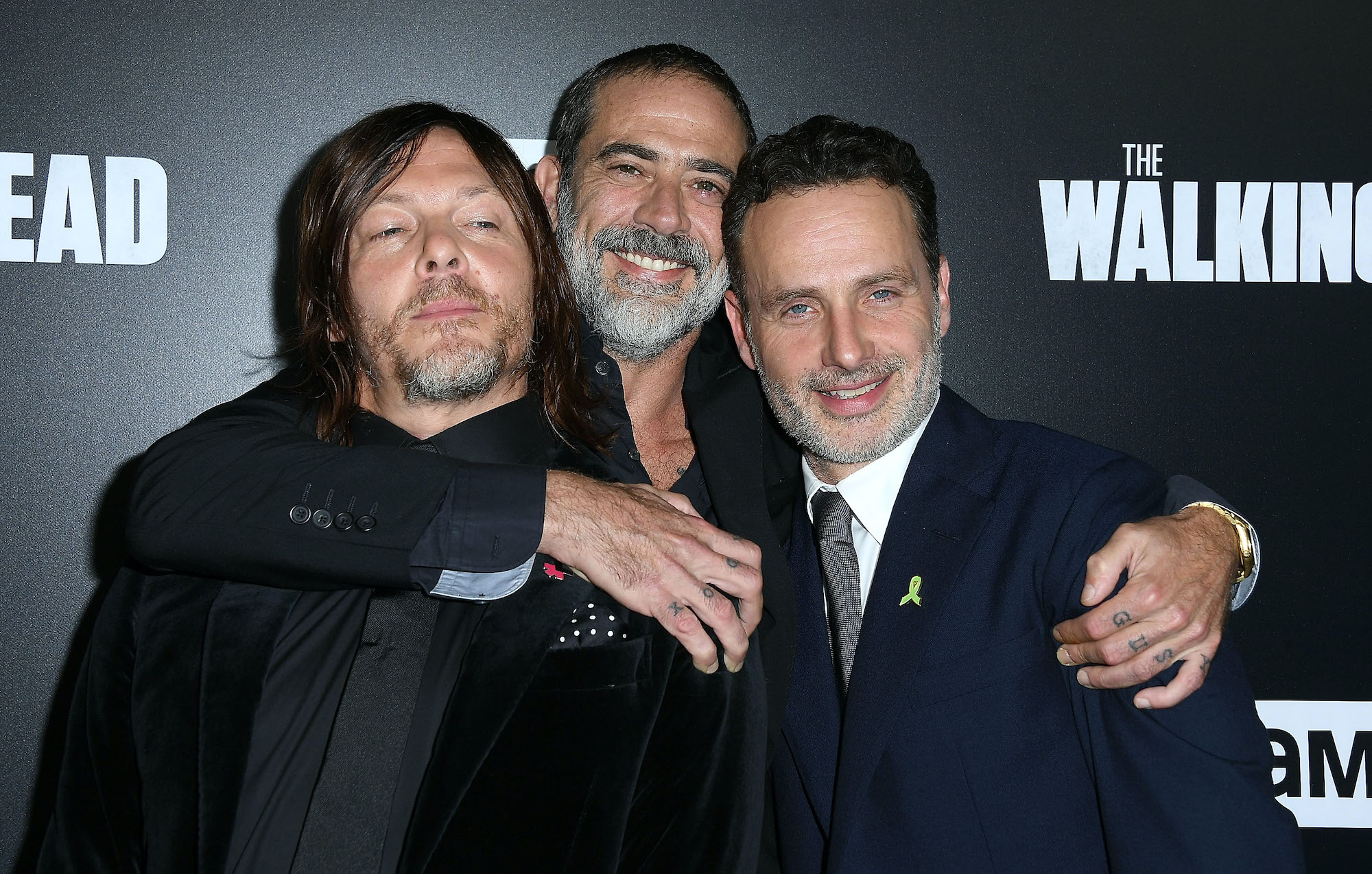 Cast members of 'The Walking Dead' smiling in front of a black background