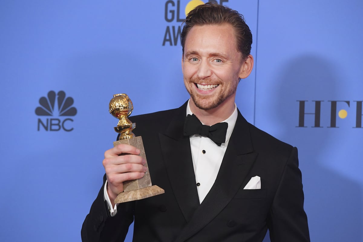 Tom Hiddleston smiles as he poses for cameras holding his Golden Globe for Actor in a Mini-Series or Motion Picture for TV