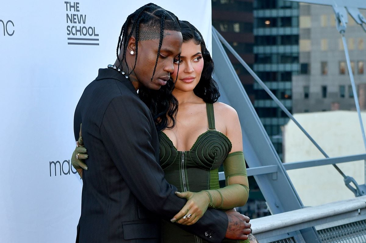 Travis Scott in a black suit and Kylie Jenner in a green dress
