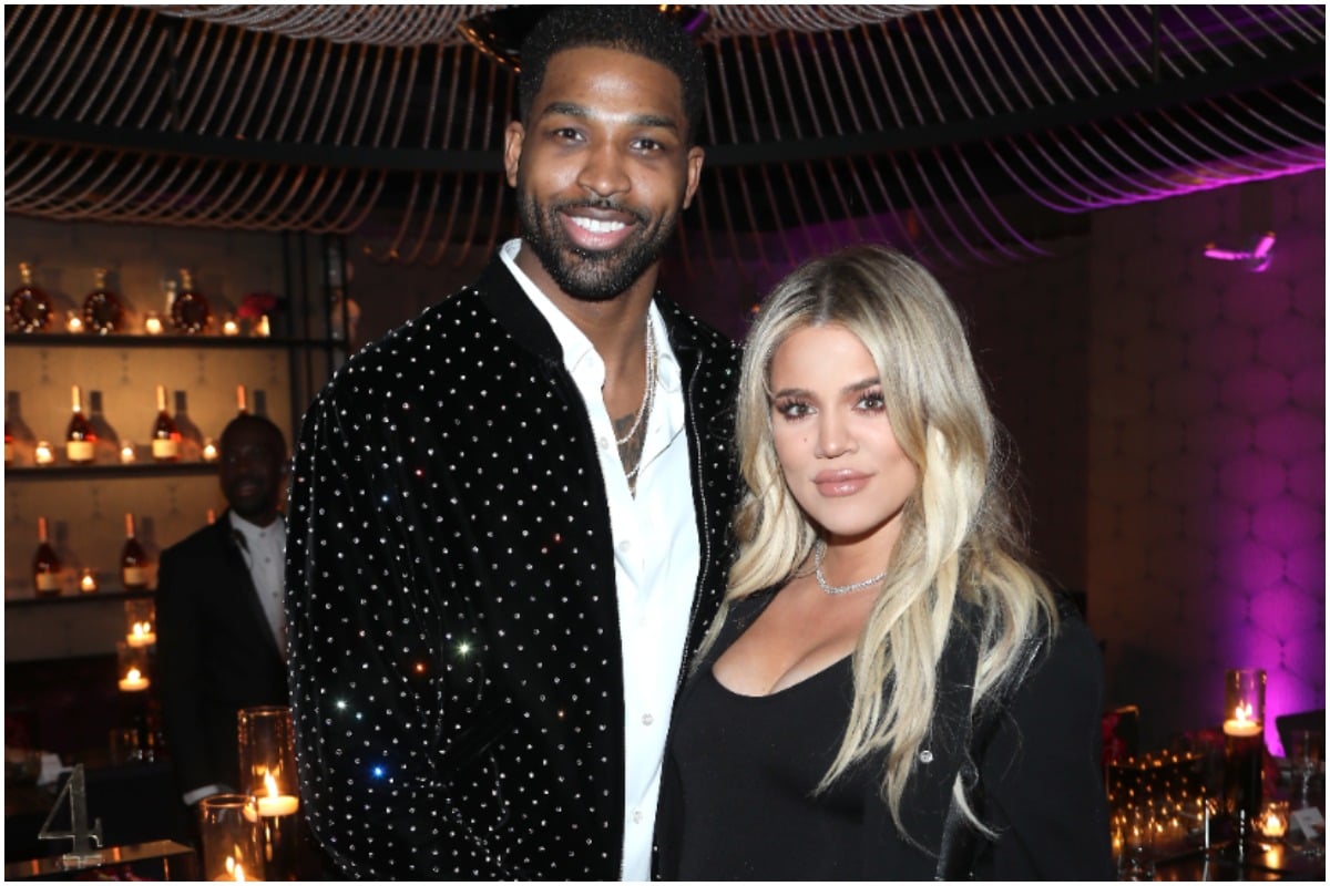 Khloé Kardashian and Tristan Thompson smiling and posing together while wearing black outfits.