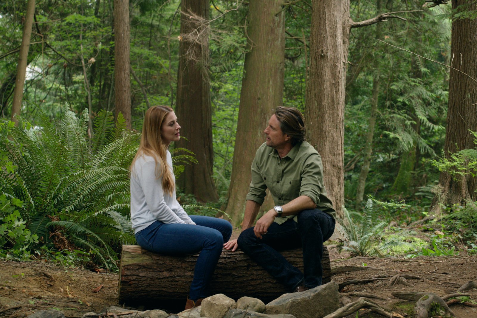 Mel and Jack sitting on a tree trunk in the woods