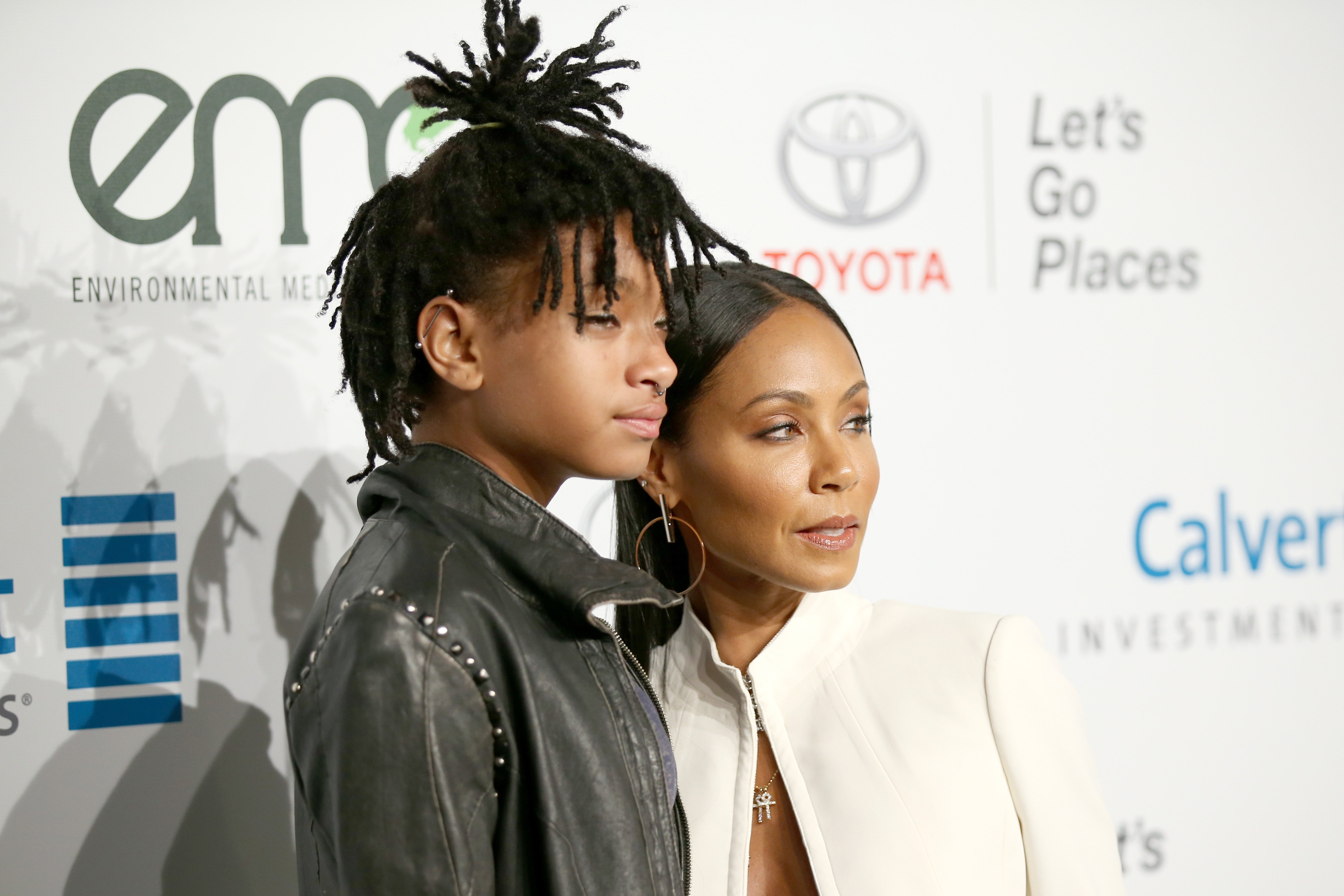 Willow Smith and Jada Pinkett Smith posing and smirking while looking away from the camera.