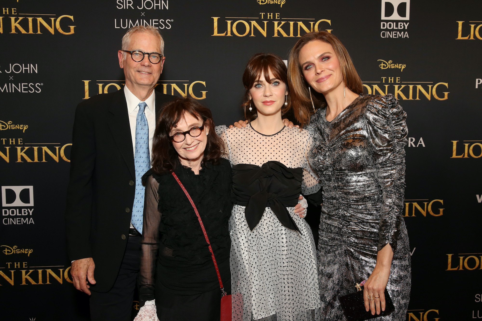 The Deschanel family smiling in front of a black background