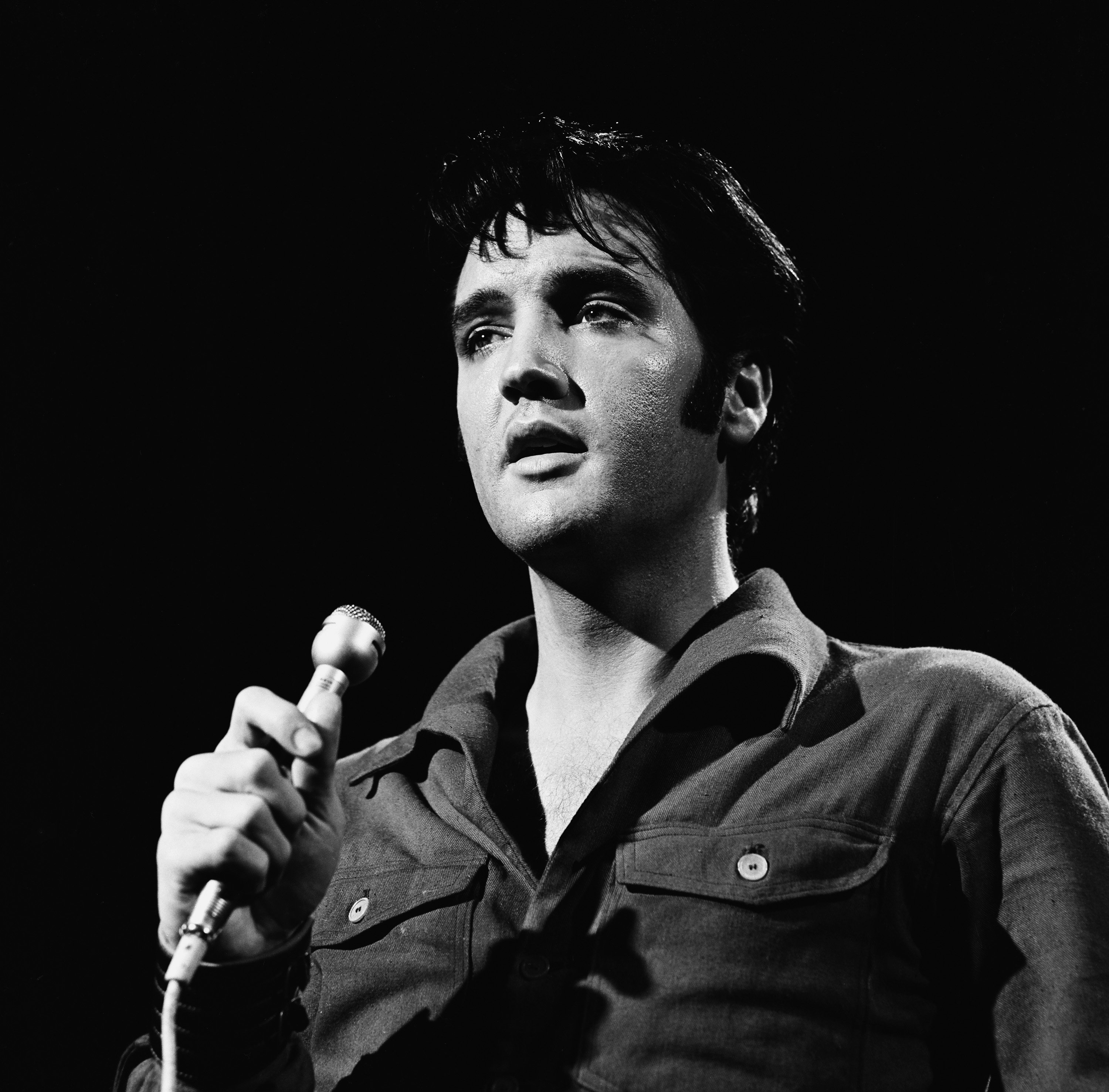 Elvis Presley performing songs into a microphone